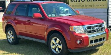 Red SUV parked on grass near a car sale sign.