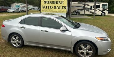 Silver sedan parked in front of a used car dealership.