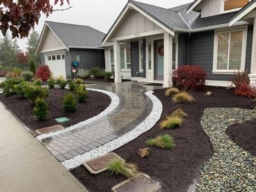 Curved front paving stone walkway with meandering gardens and rockery 