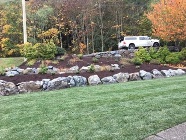 Sloped front yard terrain with rock wall gardens and new grass 