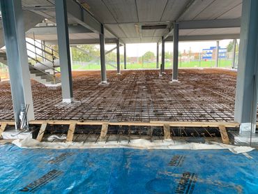 Construction site with steel rebar grid and concrete structure.