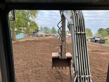 View from excavator digging on a construction site with dirt and machinery.