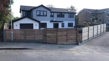 Modern two-story house with wooden fence and gate surrounding the property.
