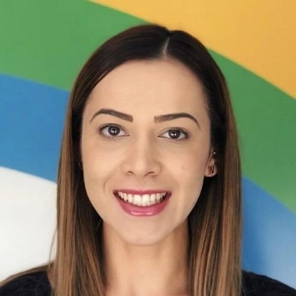 Smiling woman with straight brown hair against colorful background.