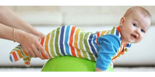 Child lying on a therapy ball receiving treatment to their legs