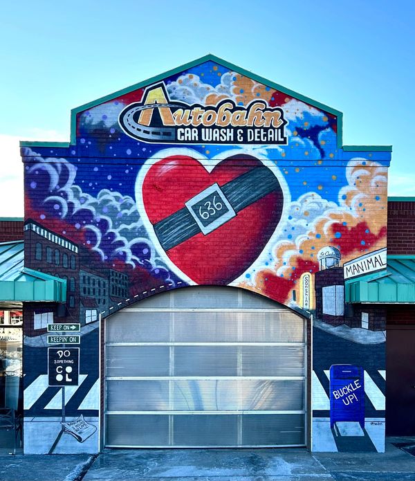 Colorful mural on car wash building with heart and safety message.