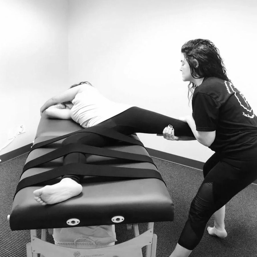 Massage Therapist stretching a client to help low back pain in black and white. 