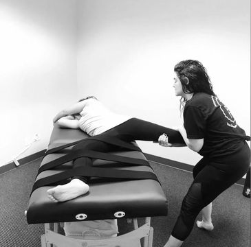 Sports massage therapist stretching a client with low back pain