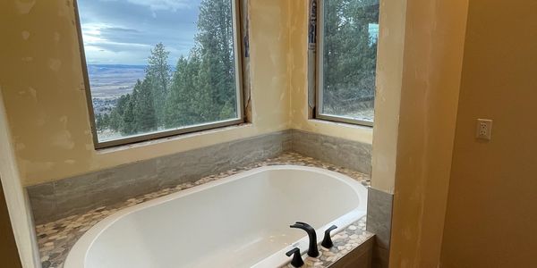 Bathroom renovation with corner soaking tub, tiled surround, and large windows overlooking Eastern O