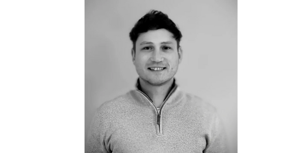 Smiling man in a light sweater against a plain background.