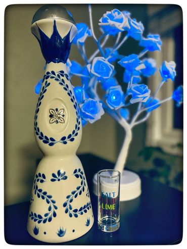 Decorative tequila bottle with a shot glass and blue illuminated rose tree.
