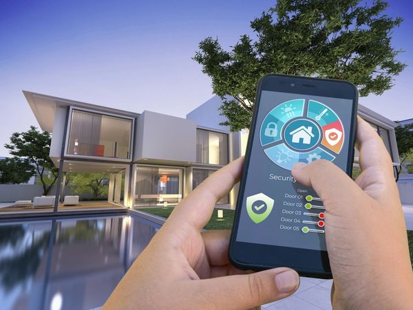 a pair of hands holding a mobile phone with an app that controls the smart home technology