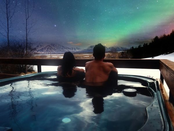 a nighttime image of a man and woman in a hot tub enjoying the night sky