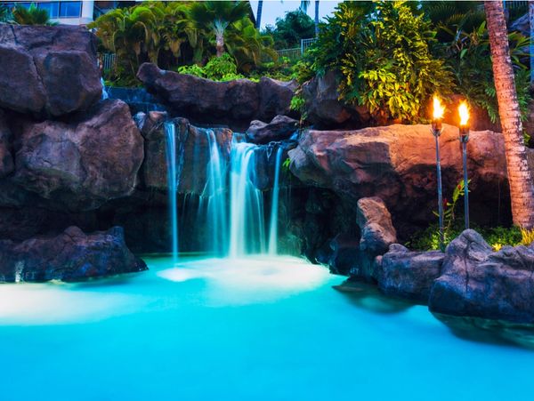 a tropical jungle themed rock facade with waterfall leading into a swimming pool