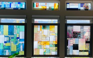 Three vibrant stained glass windows with geometric designs in blue, yellow, and multicolor.
