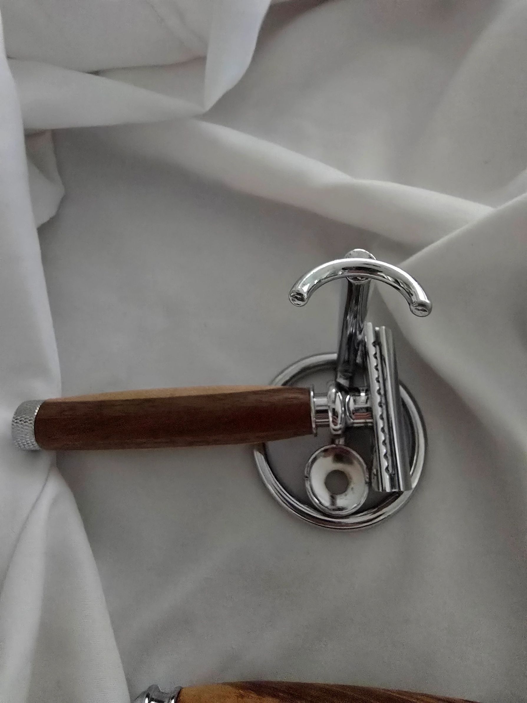 Classic safety razor with wooden handle on white fabric.