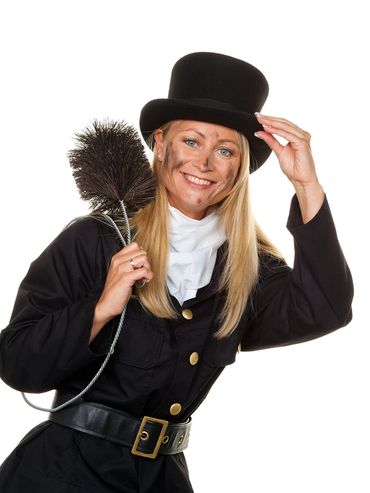Woman dressed as a chimney sweep holding a brush and tipping her hat.
