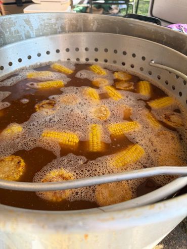 Corn boiling in a large pot of seasoned broth.