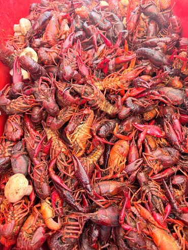 A large pile of cooked crawfish with some potatoes mixed in.