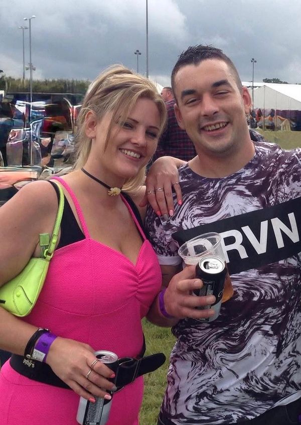 Smiling couple enjoying drinks outdoors at a casual event.