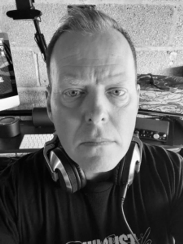 Black and white selfie of a serious man wearing headphones around his neck.