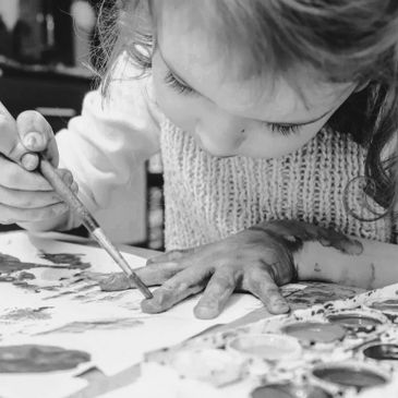A child painting with a brush, focused and creative.