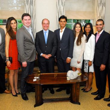 Group of seven people standing in a room, dressed formally.