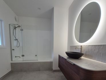 Completed Maungatapere bathroom with walnut look vanity, concrete vessel basin and round mirror