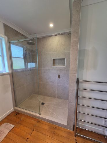 Completed bathroom in Waitotira with a tiled shower, glass enclosure, and chrome heated towel rail.