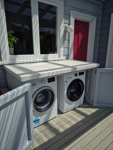 Outdoor laundry in Regent, Whangārei, with built-in cabinetry, tiled benchtop and appliances.