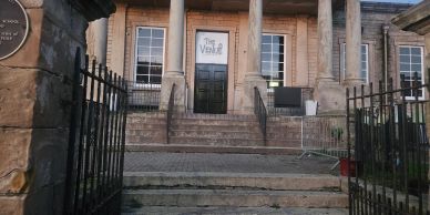 Front entrance of a historic building with iron gates and stone steps.