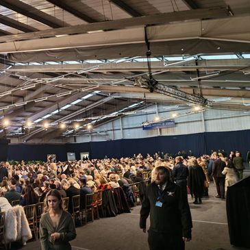 Large indoor gathering with many people seated.