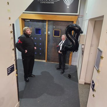 Two security guards standing near doors with a black balloon shaped like the number 8.
