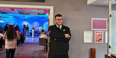 Security guard standing with arms crossed near an event hall.