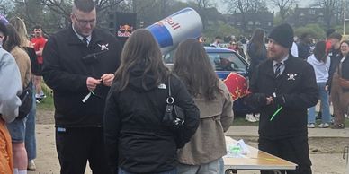 Two men in black jackets talking to two women near a table outdoors.
