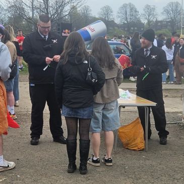 People standing in line near a promotional table outdoors.
