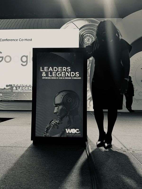 Silhouette of a woman beside a 'Leaders & Legends' tech event sign.