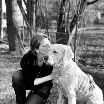 Woman kissing her dog outdoors in a black and white photo.