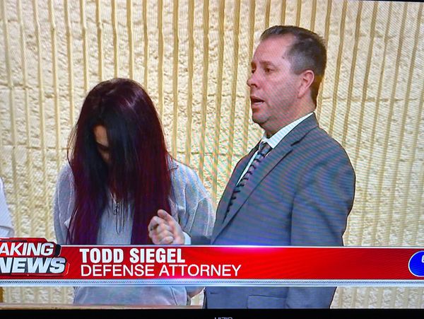 Defense attorney Todd Siegel speaks while a woman stands with her head down.