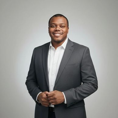 Confident man in a dark suit smiling against a gray background.