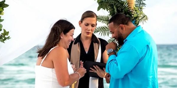 Bride, groom, wedding officiant on the beach. Photo by Photography and Art by Sara Lynsey.