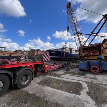 A crane lifting a boat named Jillian under a blue sky.