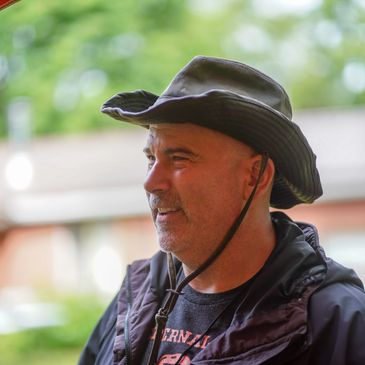 Man wearing a black wide-brimmed hat and jacket outdoors.