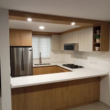 Modern kitchen with wooden cabinets and white countertops.