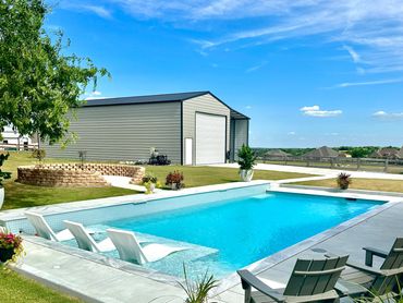 Modern backyard pool with lounge chairs and a clear blue sky.