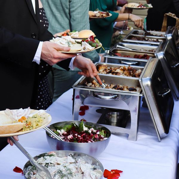 People serving themselves food from a buffet at a formal event.