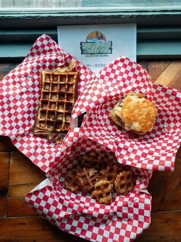 Waffles and a biscuit sandwich served on red and white checkered paper.