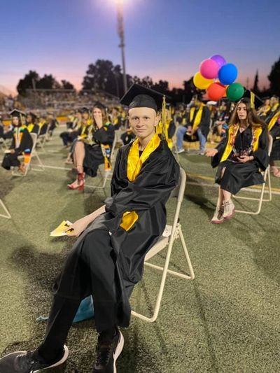 A man wearing graduation uniform and sit on the chair