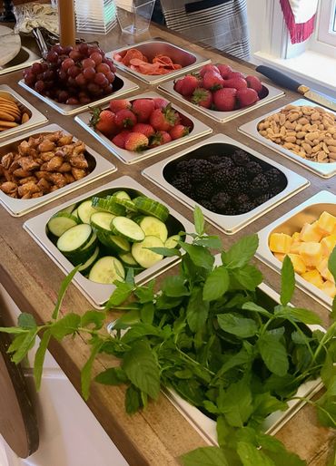 A colorful assortment of fresh fruits, veggies, nuts, and snacks neatly arranged in trays.