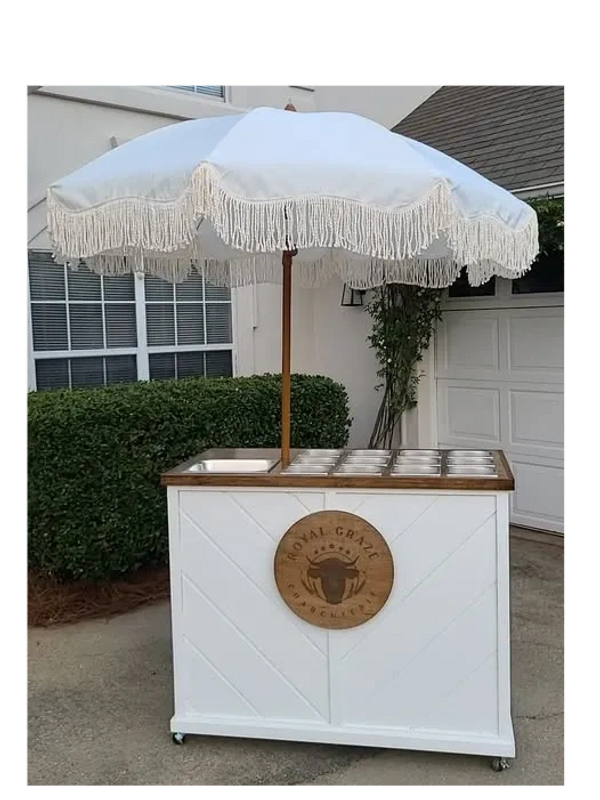 Stylish white outdoor bar cart with umbrella and wooden accent.